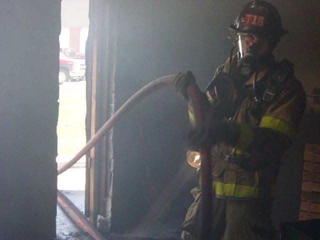 Firefighter advances hose line at a live fire training drill.