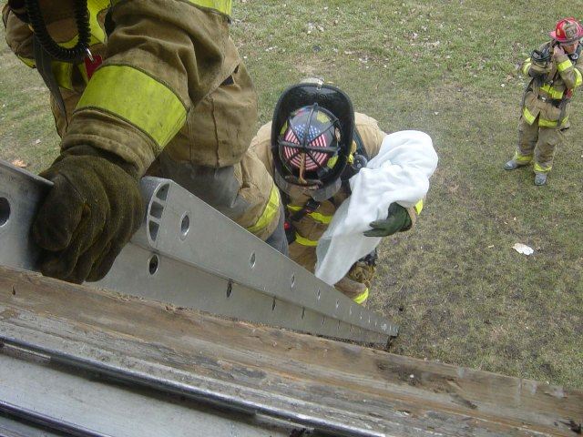 Firefighter removes a baby mannequin down a ladder at practical training drill.